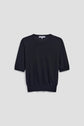 A plain black short-sleeve knit sweater in soft laine mérinos with a classic pull col rond, displayed on a light gray background.