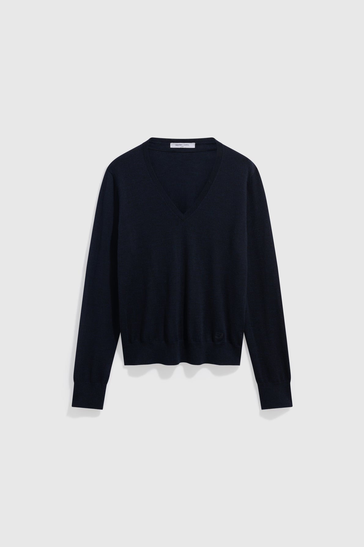 A plain, long-sleeve, dark navy blue V-neck sweater is displayed against a light gray background. This pull bleu marine homme features ribbed cuffs and hem, with a relaxed fit and simple design. Crafted as a pull fin décontracté, it offers versatile style for any casual occasion.