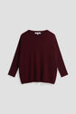 A loose-fitting, long-sleeve, dark burgundy pull en cachemire with a crew neckline is displayed flat against a light gray background.