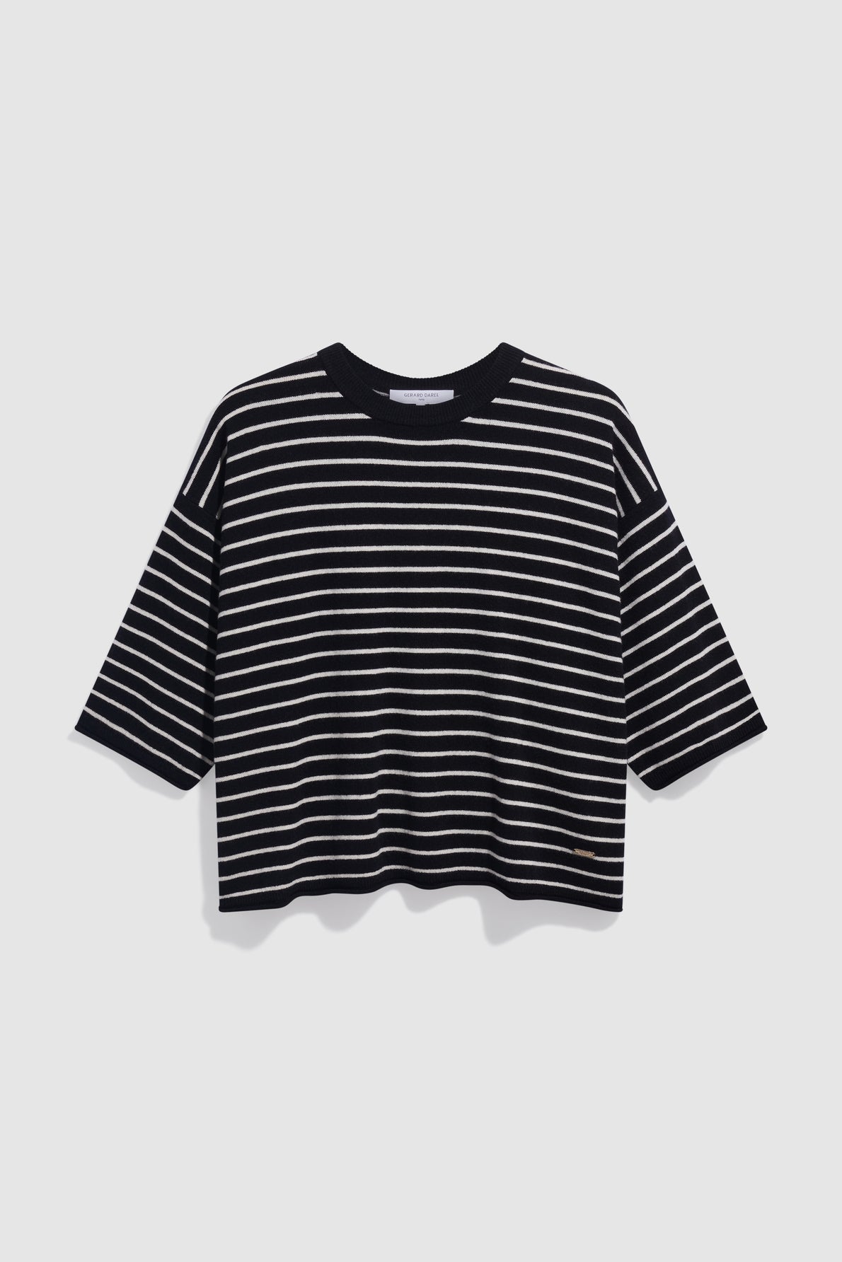 A loose-fitting, black T-shirt with white horizontal stripes and short sleeves, reminiscent of a pull noir écru style, is displayed against a plain, light grey background.