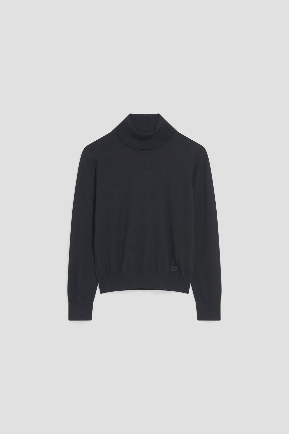 A black, long-sleeve pull col roulé en laine mérinos is laid flat on a plain, light gray background.