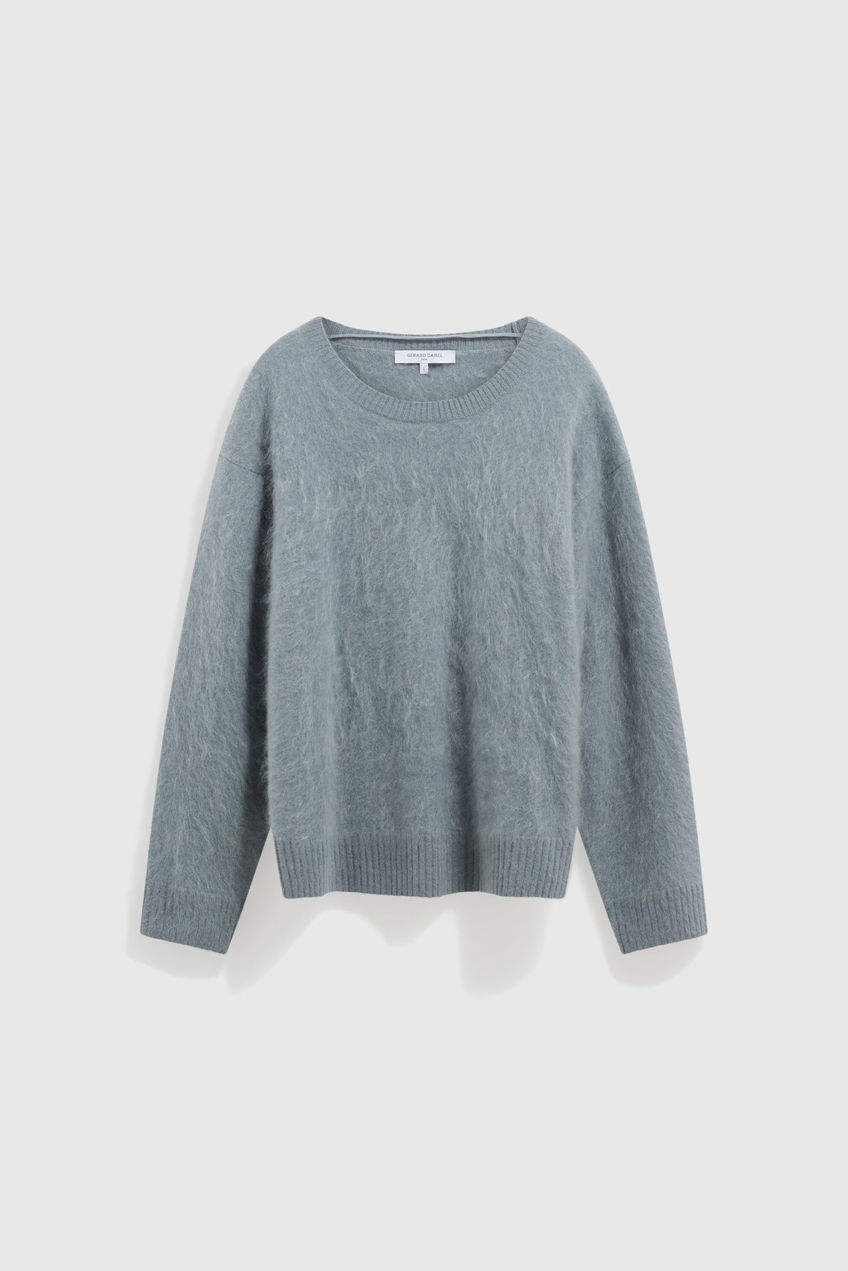 Light blue, long-sleeve, fuzzy knit sweater with a crew neckline, ribbed cuffs, and ribbed hem displayed against a plain white background. This pull bleu grisé features a cachemire brossé texture, making it an ultra soft and comfortable pull ultra doux for everyday wear.