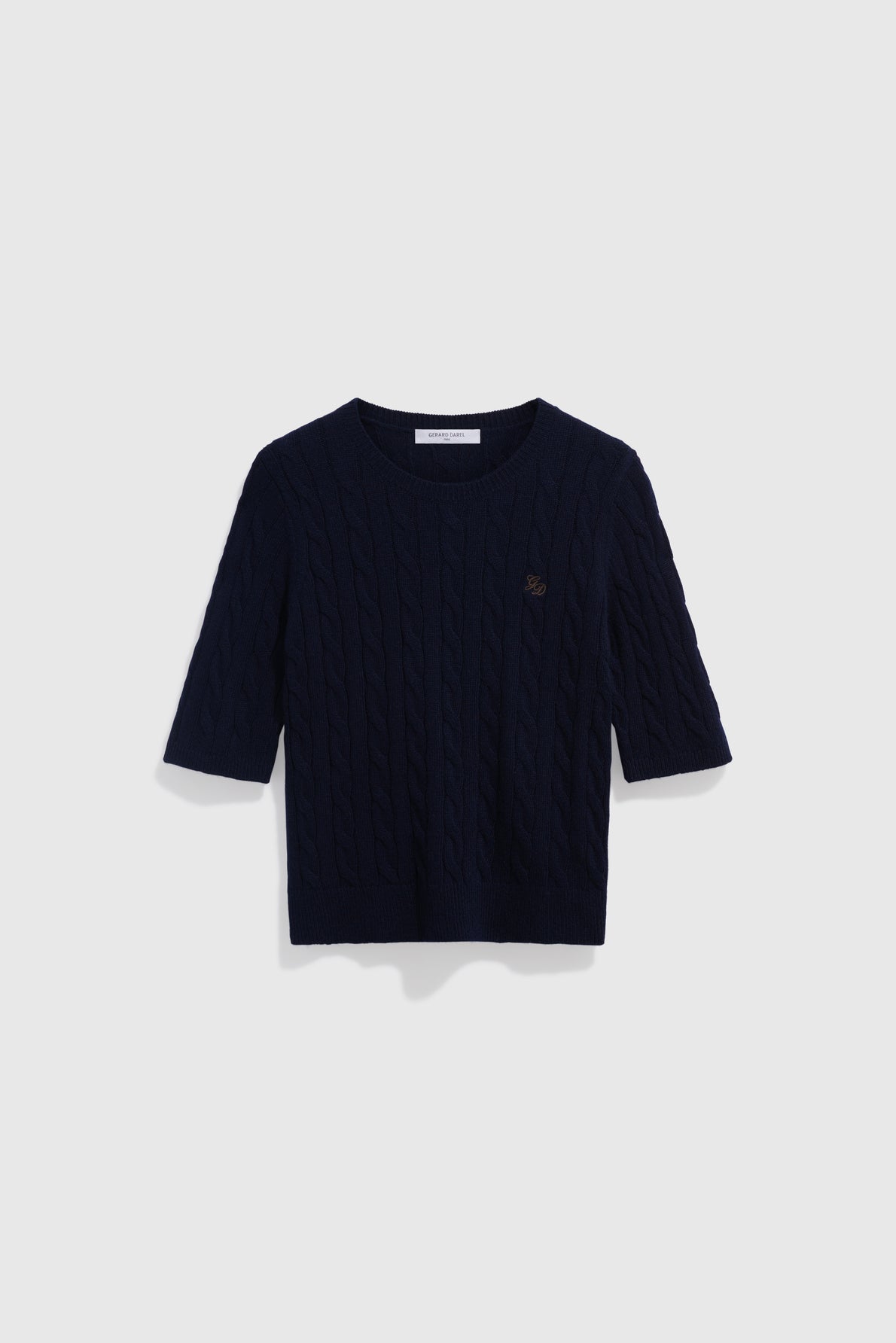 A navy blue, short-sleeved, cable-knit sweater crafted from luxurious laine mérinos, featuring a round neckline and a small embroidered logo on the left chest, displayed on a plain white background.
