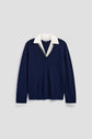 A pull laine bleu marine à col V, superposé sur une chemise blanche à col chemise amovible, est présenté sur un fond gris clair.