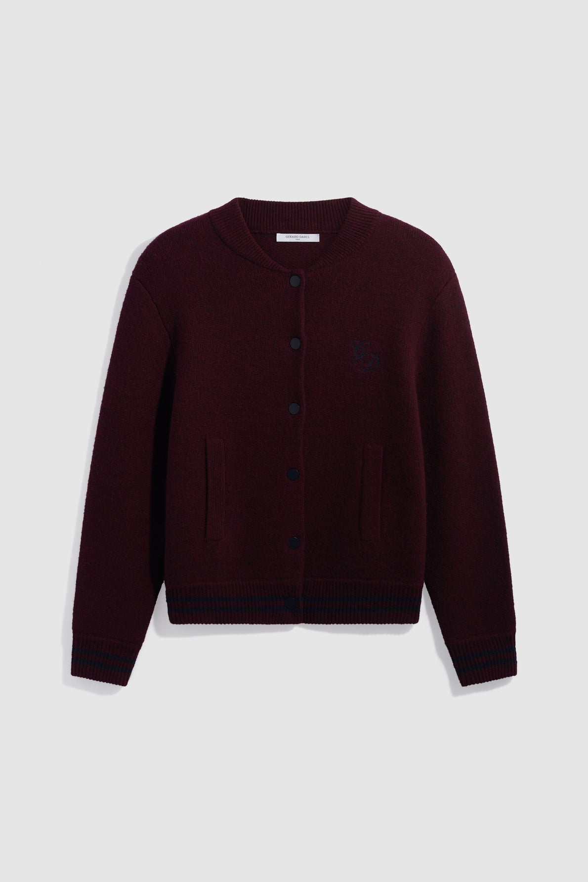 A bordeaux knit cardigan with black buttons, ribbed cuffs and hem, two front pockets, and a subtle embroidered logo on the left chest, reminiscent of a classic gilet en laine, displayed flat on a light gray background.