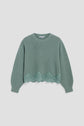 Green knit sweater with long sleeves, ribbed cuffs, and a round neckline. The hem features a scalloped lace trim with floral details, adding a touch of elegance to this pull dentelle. This cozy pull laine femme is displayed against a plain white background.