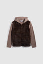 Brown, hooded jacket with ribbed knit sleeves and back, and a faux fur front panel. This stylish gilet zippé features a comfortable capuche, perfect for cooler days. The jacket is displayed on a plain light gray background.