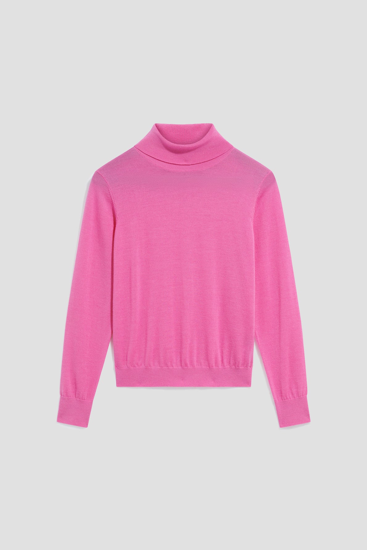 A plain, long-sleeved, bright pink pull col roulé sweater in soft laine mérinos is laid flat on a light gray background.