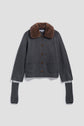 A gilet gris en cachemire with front pockets, brown buttons, a brown col fausse fourrure collar, and long detached sleeves with thumb holes, displayed on a plain background.