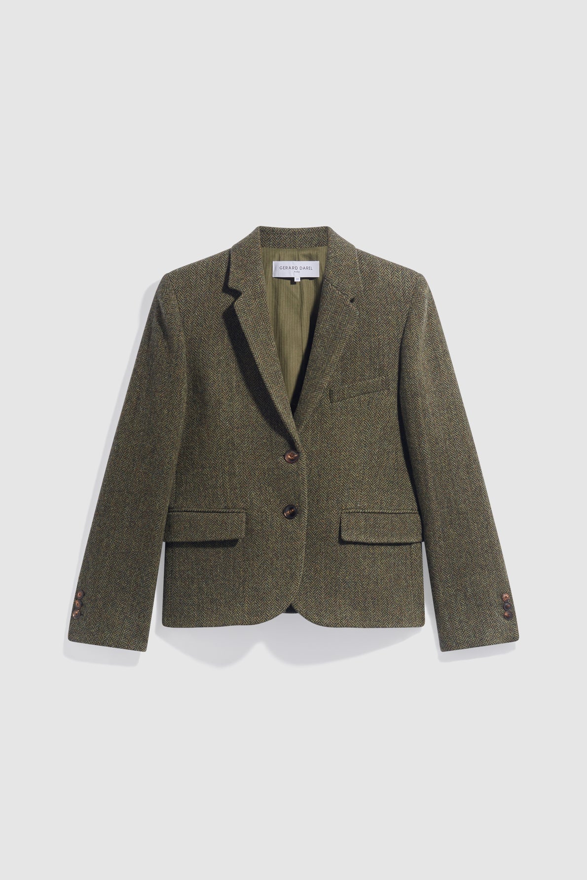A single-breasted, olive green tweed veste de tailleur with notched lapels, crafted from pure laine vierge in a subtle motif à chevrons, featuring two front flap pockets, a chest pocket, and dark buttons, displayed on a plain white background.