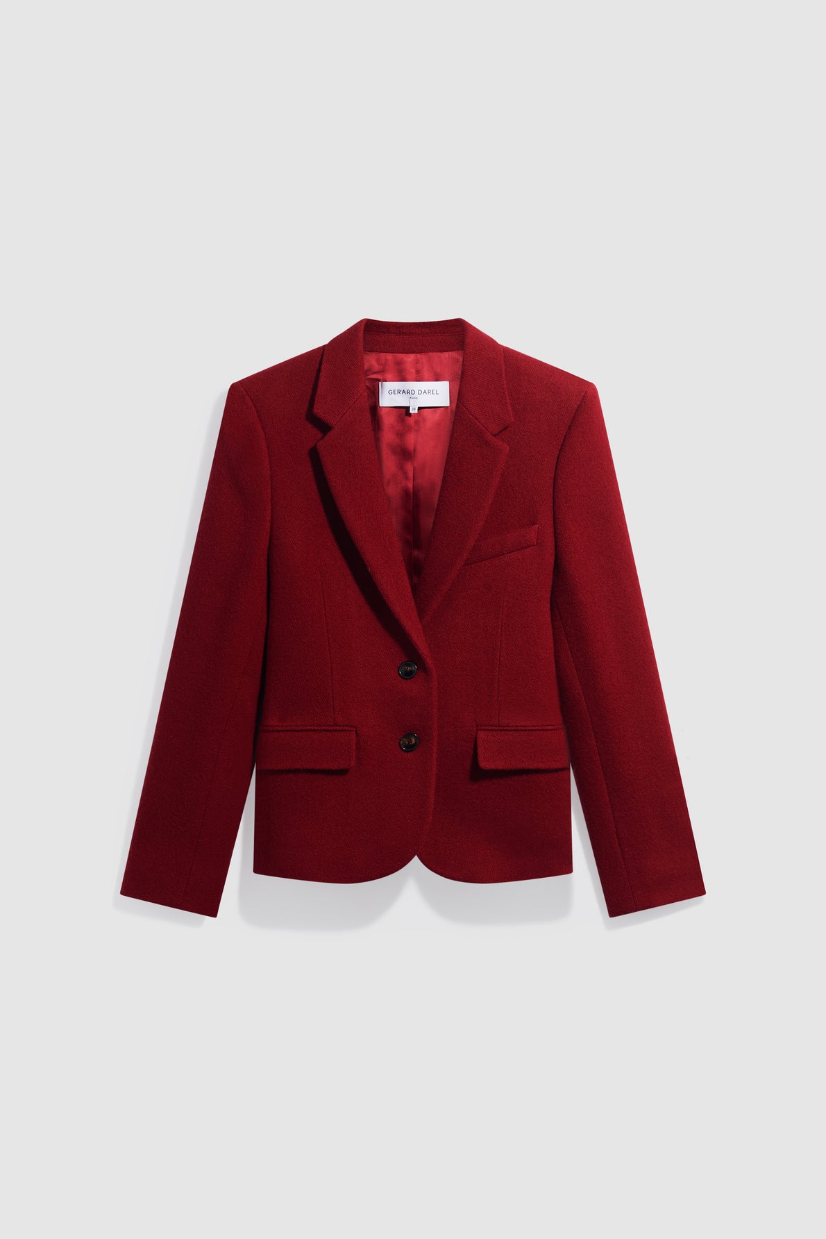 A tailored, deep red blazer—perfect as a veste rouge femme—with a notched collar, two front buttons, flap pockets, and a chest pocket, displayed on a plain light gray background.