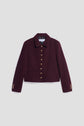 A cropped, dark burgundy veste tweed bouclé with gold buttons down the front and on the sleeves, featuring a collar and two front pockets, displayed on a plain light gray background.
