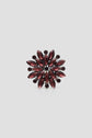 A ring with a starburst design featuring marquise-shaped dark red gemstones and small round stones arranged symmetrically, set in a dark metal band, reminiscent of the delicate artistry found in a broche corolle.