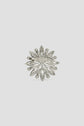 Silver brooch in the shape of a snowflake with a central clasp, featuring leaf-like and round decorative elements, set against a plain light gray background—an undeniably broche élégante, perfect for adding refined charm to any ensemble or veste.