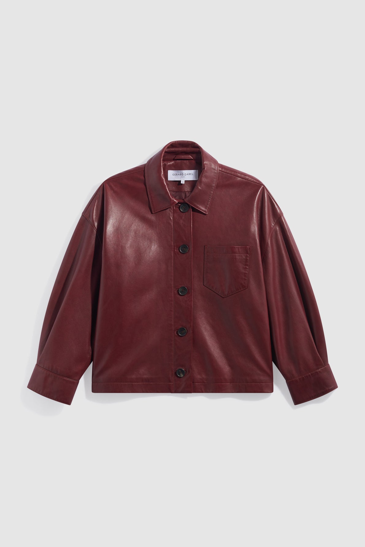 A maroon faux leather surchemise femme with a collar, front buttons, long sleeves, and a single chest pocket, displayed against a light gray background. This élégante veste bordeaux effortlessly combines style and versatility for any occasion.
