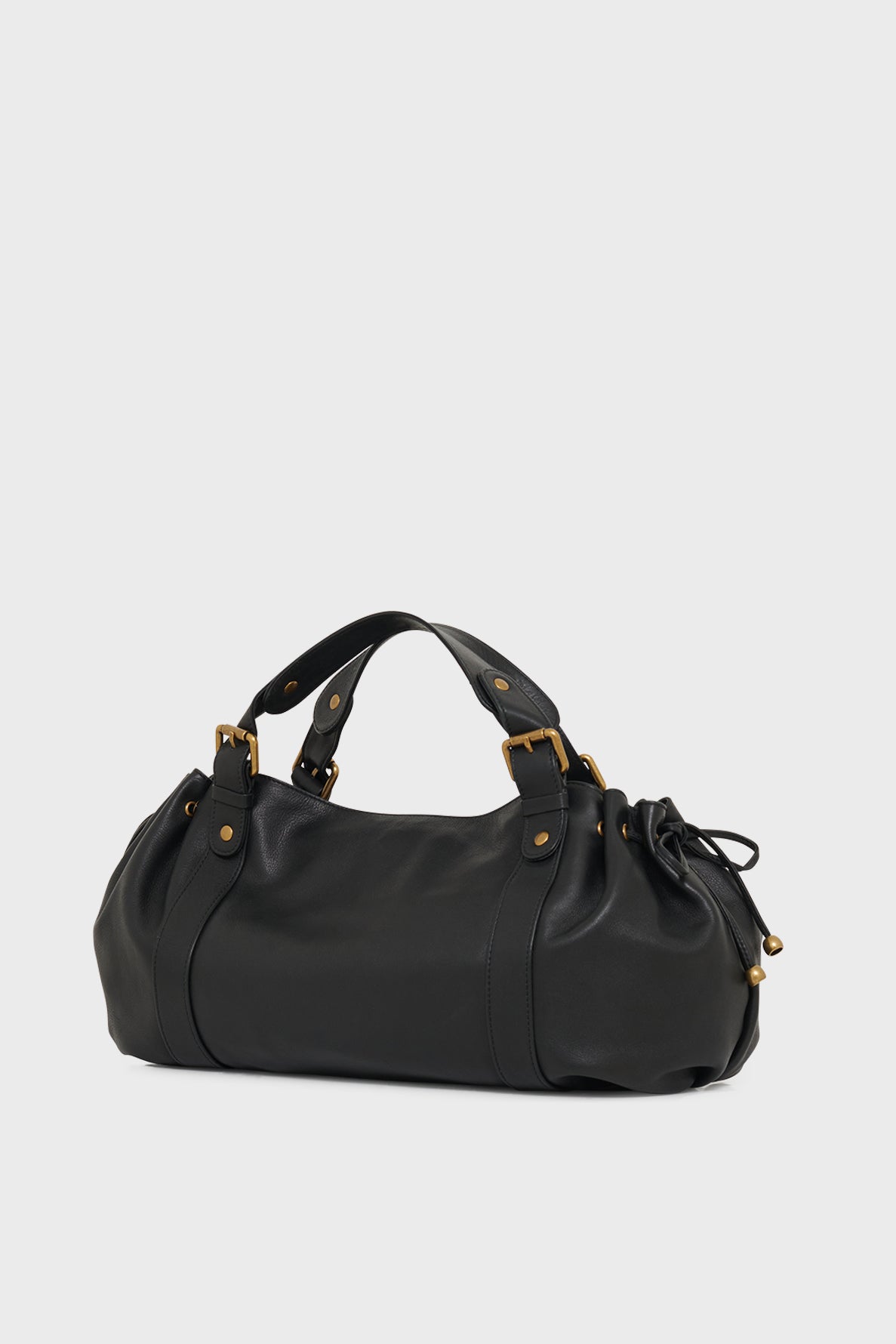 Black leather handbag with gold hardware, two short handles, and a drawstring detail on one side, set against a plain light gray background—a timeless sac à main crafted from cuir délicat that exemplifies the refined artistry of maroquinerie Darel.