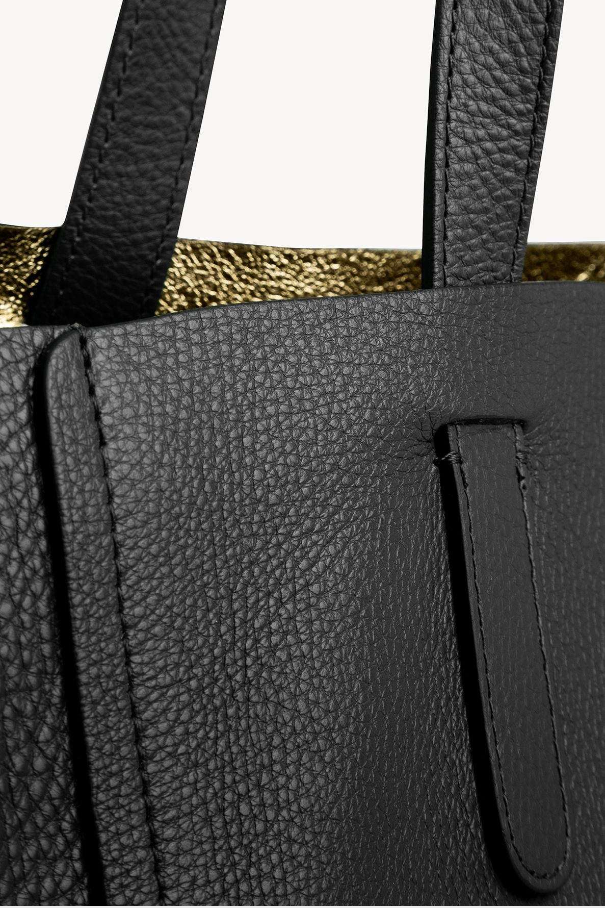 Close-up of a sac à main élégant crafted from black pebbled leather, featuring sturdy handles and a glimpse of luxurious metallic gold lining inside.
