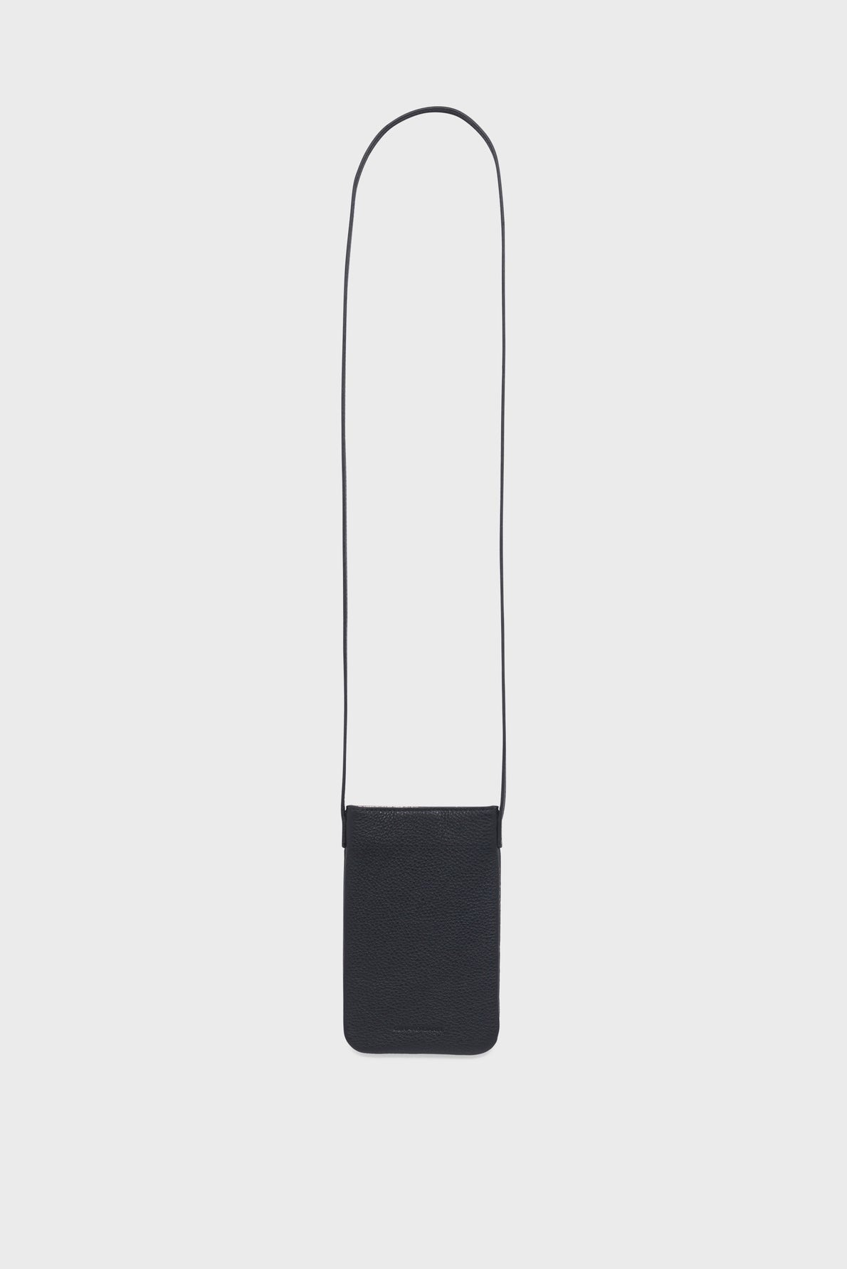 A small black porte-téléphone in cuir grainé with a long thin strap, designed to be worn around the neck; displayed on a plain white background. This accessoire tendance effortlessly combines practicality and style.