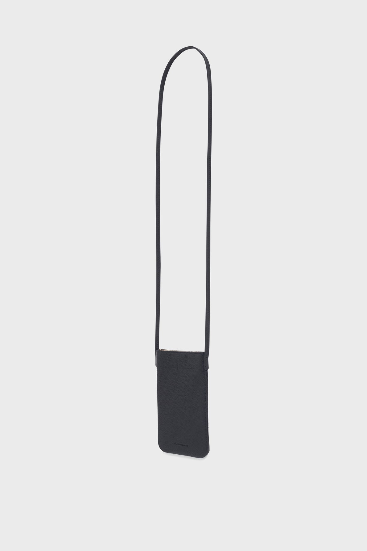 A minimalist black crossbody pouch crafted from cuir grainé, with a long, thin strap, displayed against a plain light gray background.