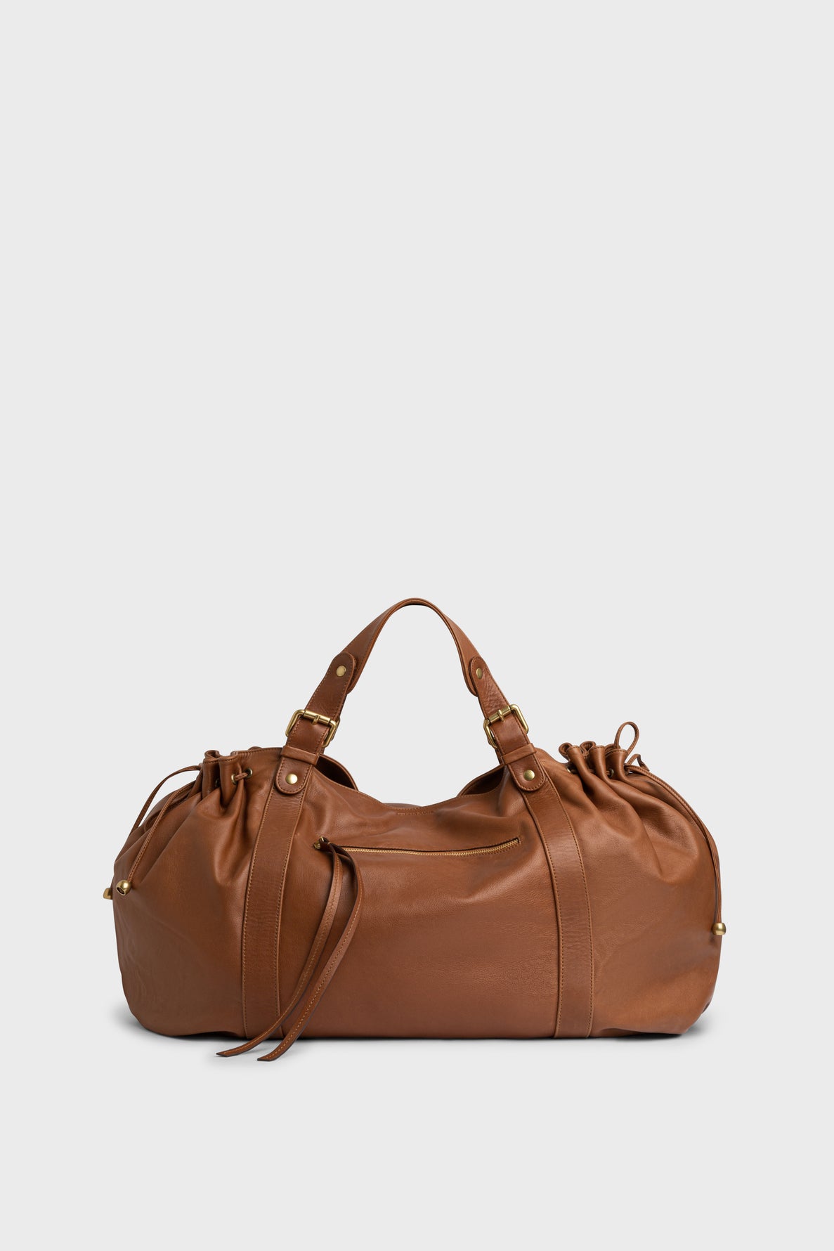 A brown cuir doux leather duffel bag with gold hardware, dual handles, side drawstring details, and a zippered top is set against a plain light background—a stylish sac à main designed for 72h getaways.