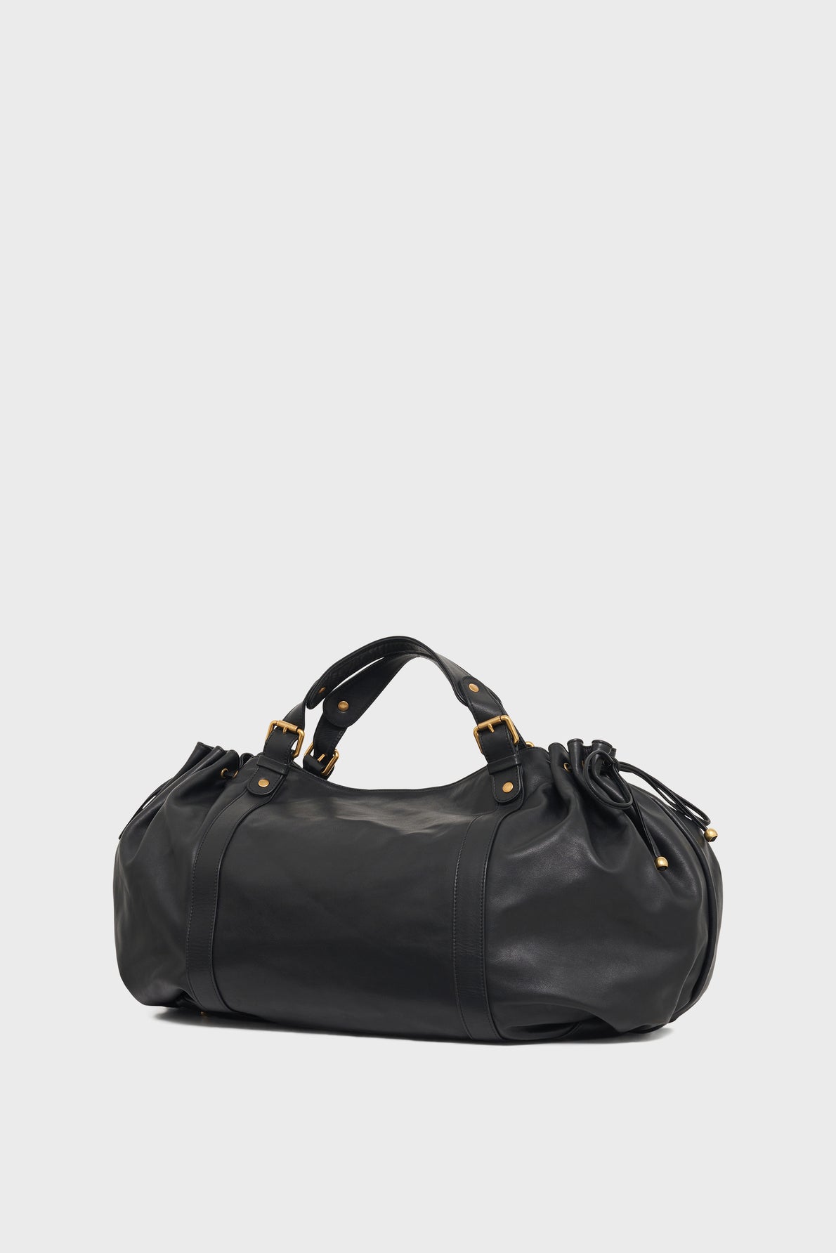 A black leather duffel bag crafted from cuir délicat, featuring gold hardware, short handles, and side drawstring details, set against a plain light gray background. Perfect as a sac à main or for a stylish 72h getaway.