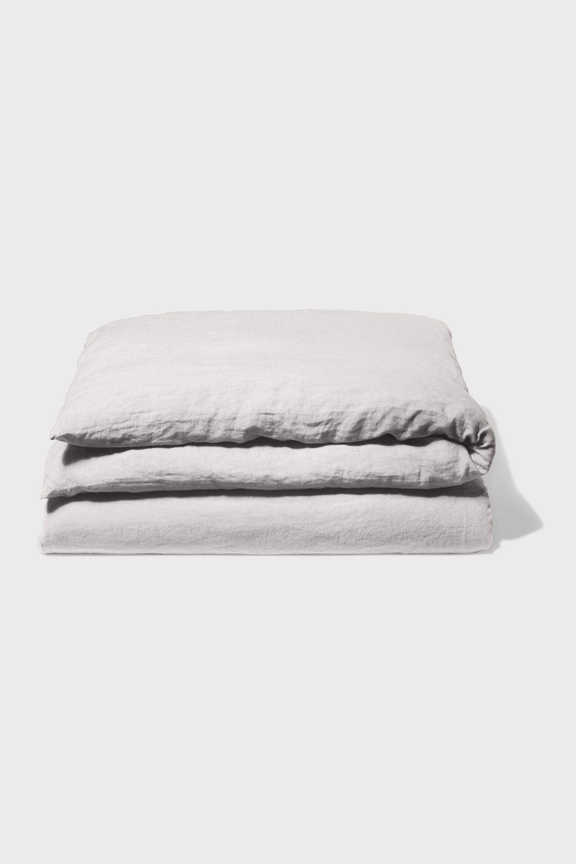 A neatly folded light gray blanket or duvet lies on a plain white background, showing its soft, textured fabric and clean edges.