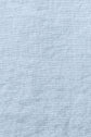 A close-up of light blue textured fabric, showing a subtle woven pattern and slight wrinkles across the surface. This drap plat lin lavé in bleu ciel is certifié OEKO-TEX, ensuring both comfort and quality for your home.