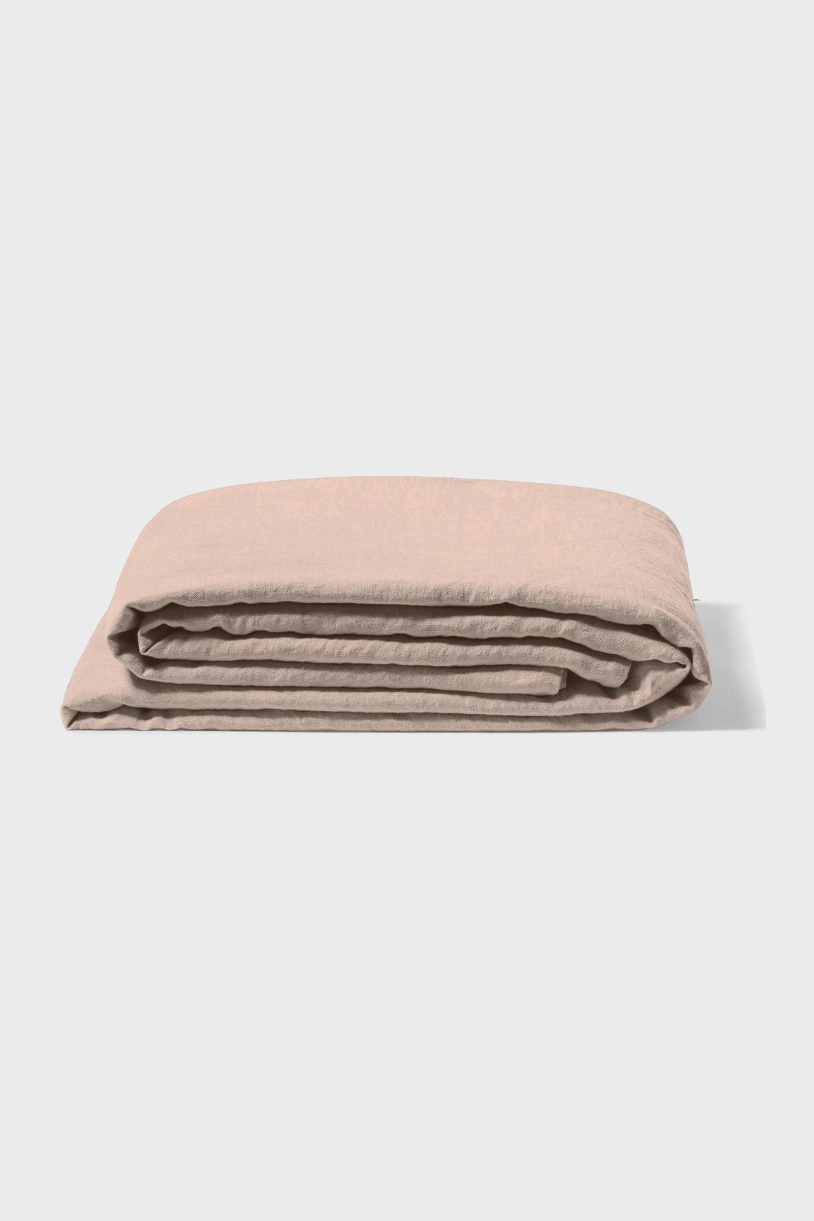 A folded beige bedsheet lies flat on a light gray background, showing smooth, soft fabric and neatly aligned edges.