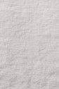 Close-up view of a plain, light gray linen fabric with a visible woven texture and subtle creases throughout the surface.