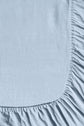 Light blue fitted bed sheet with gathered, elastic edges seen from above, forming a curved border on a flat surface. The fabric appears soft and slightly textured.