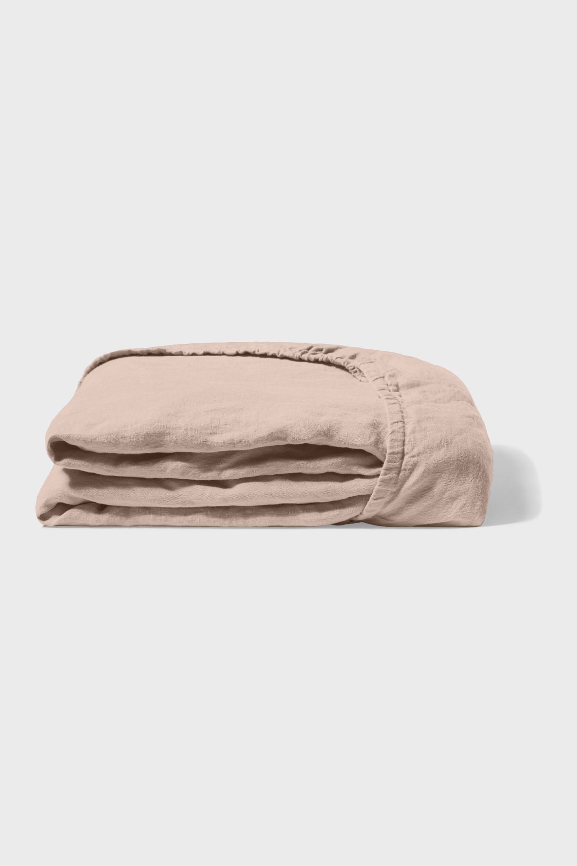 A folded, light beige fitted sheet with visible elastic edges, placed on a plain white background.