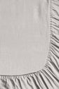 A close-up of a light gray fitted bedsheet shows smooth fabric in the center and gathered elastic edging along the side.