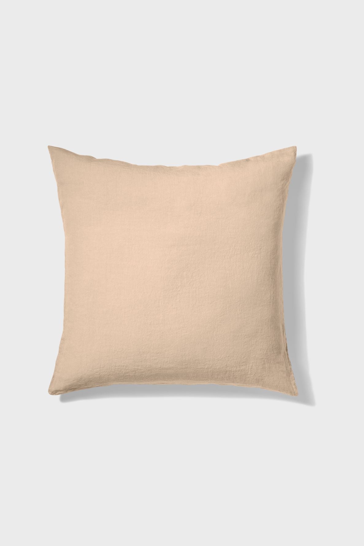 A square beige pillow with a soft, textured fabric is shown against a plain light gray background.