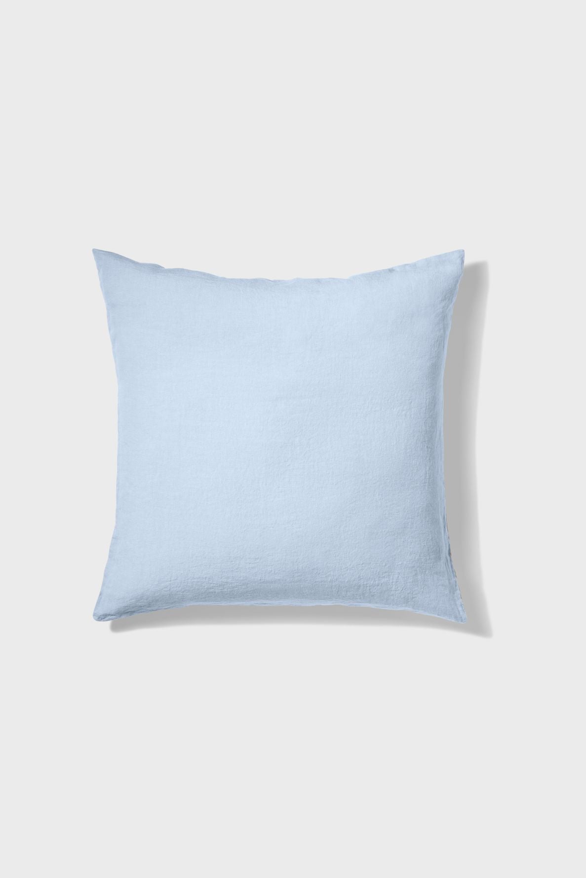A square, light blue pillow on a plain white background, casting a soft shadow to the right.