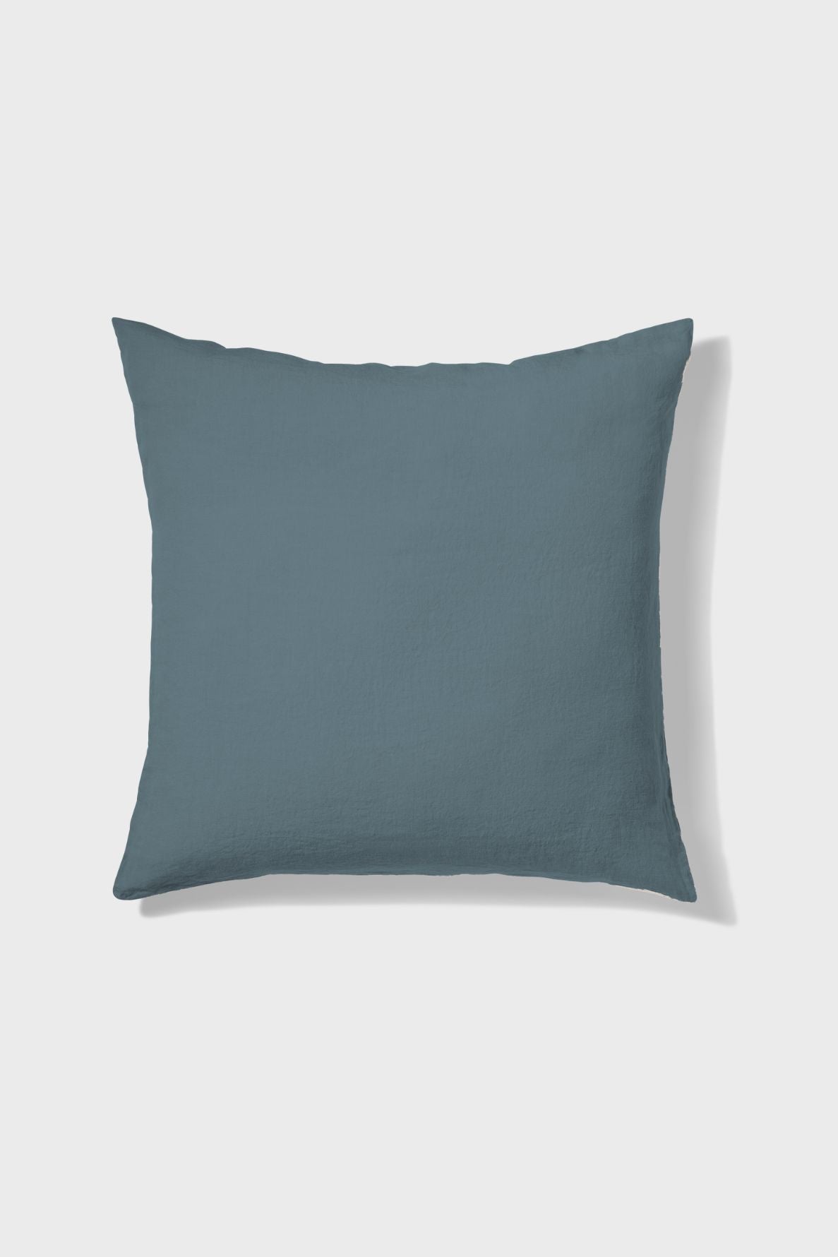 A square, solid slate-blue throw pillow is shown against a plain white background.