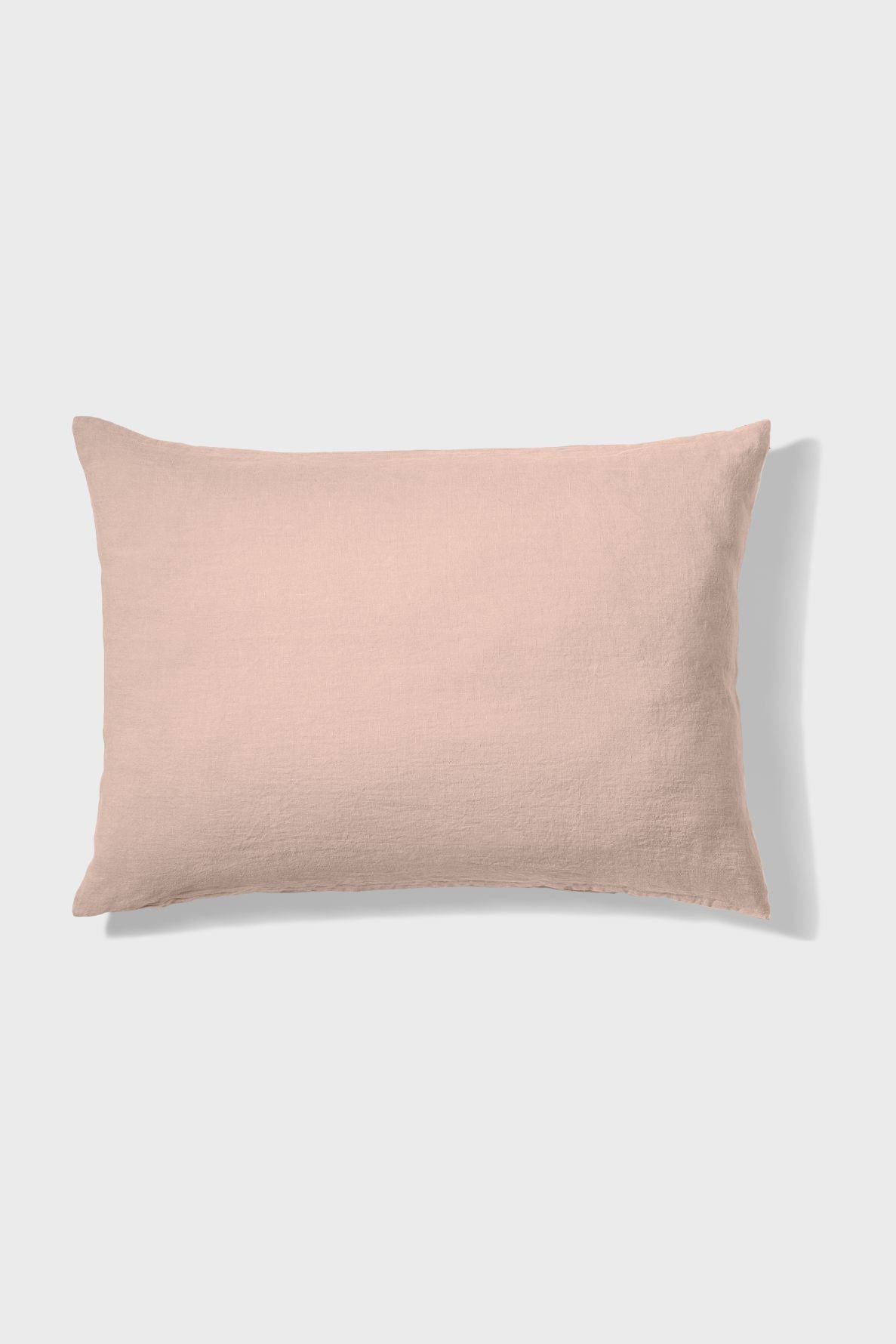 A rectangular, light pink pillow with a subtle textured fabric, placed on a plain white background.
