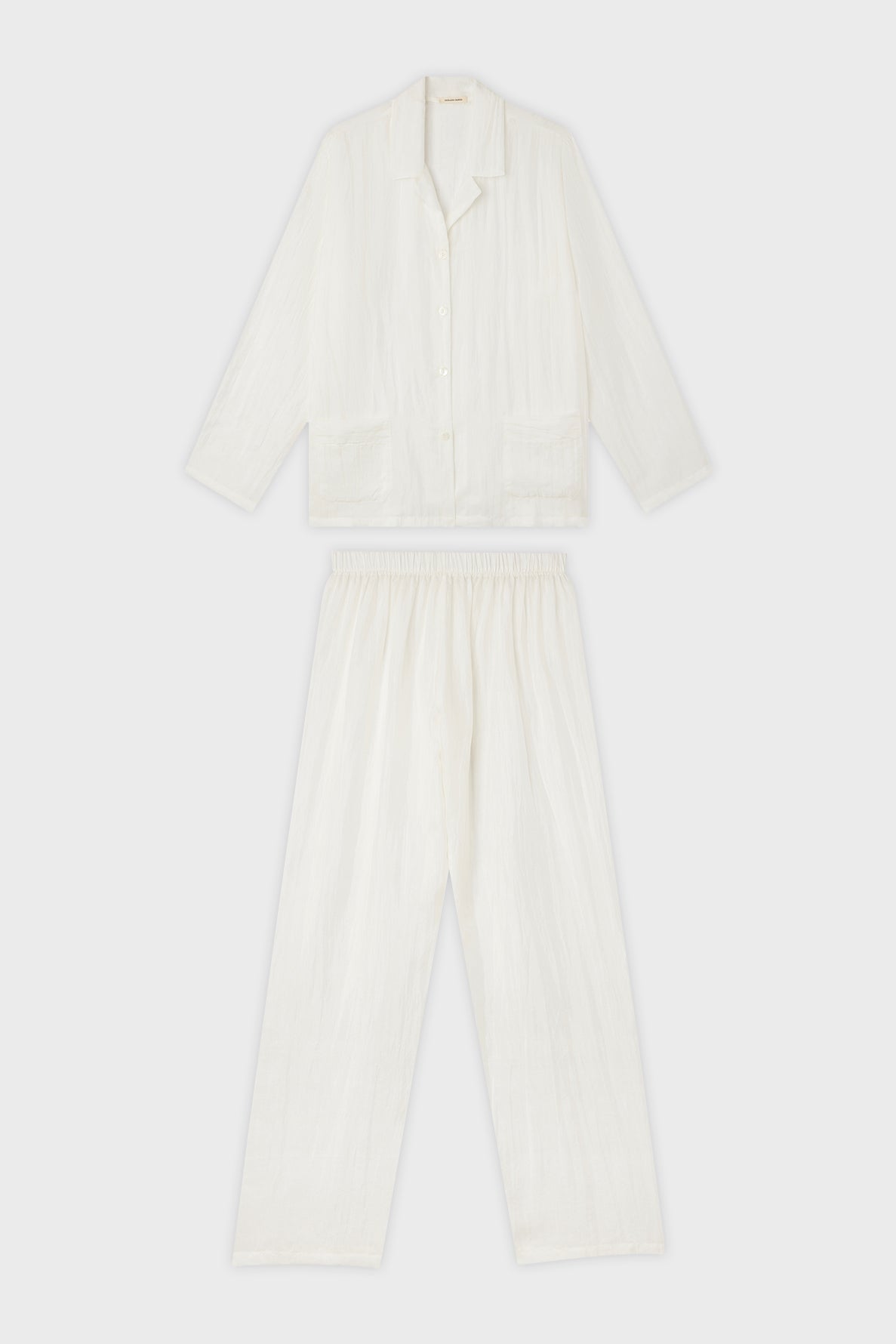 A matching white pajama set with a long-sleeve button-up top and elastic waist pants, both made from a lightweight, textured fabric, displayed on a plain background.