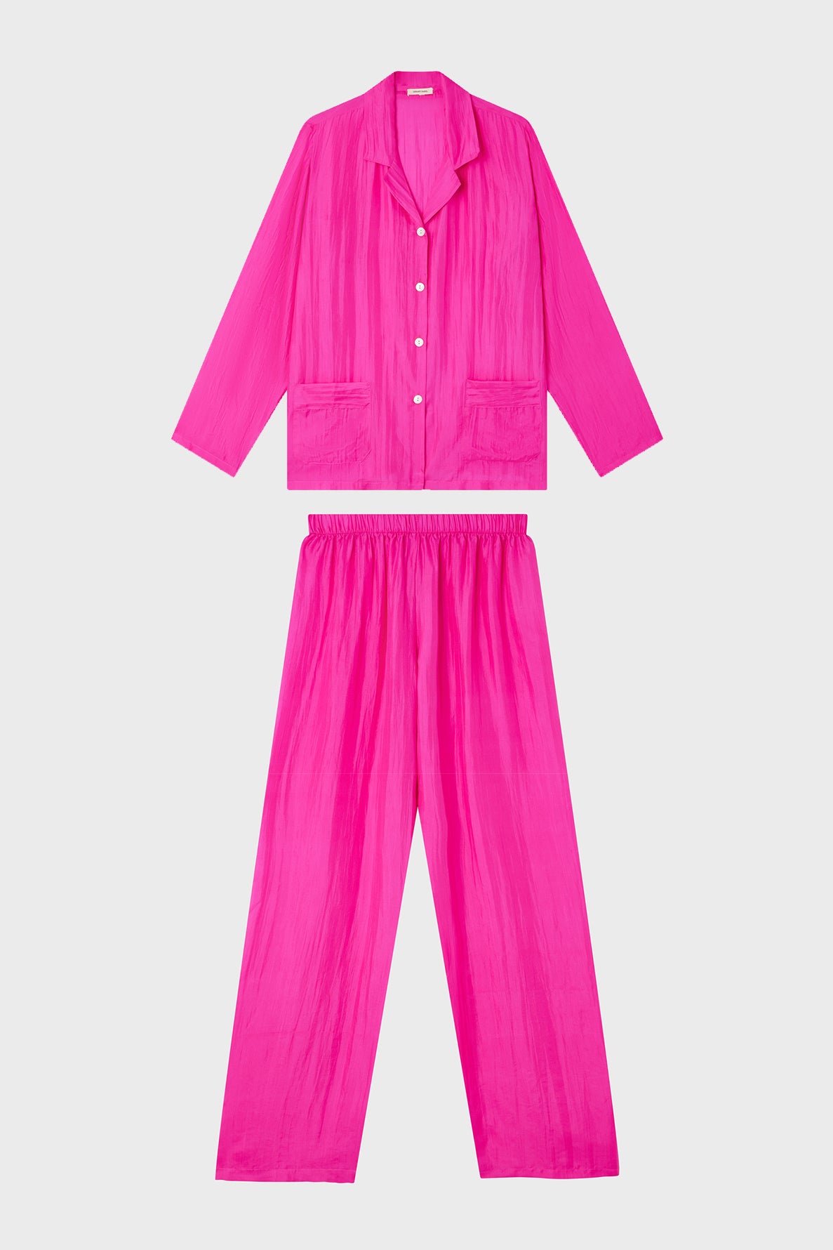 A matching set of bright pink pajamas with a long-sleeve button-up top and loose-fitting pants, both made from a lightweight, crinkled fabric, displayed on a plain white background.