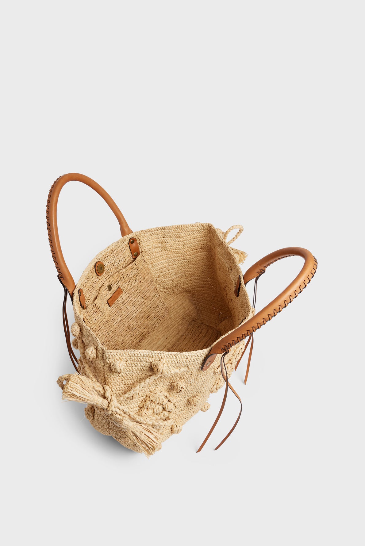 Woven straw tote bag with round leather handles, tan leather accents, and a spacious open interior—this elegant sac à main raphia is shown from a top-down angle against a plain background.