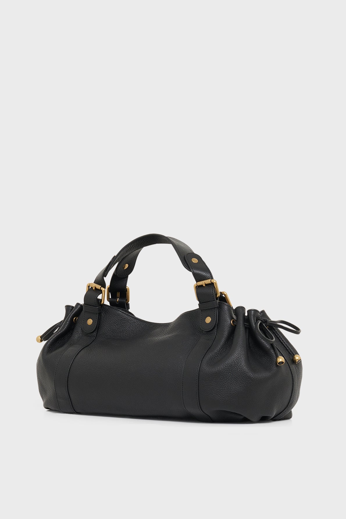 A black cuir grainé sac à main with gold hardware, dual handles, and gathered side details, displayed on a plain white background—a timeless piece of maroquinerie Darel craftsmanship.