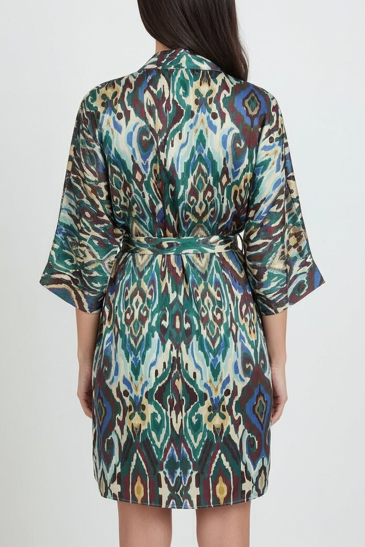 A person wearing a short, belted robe with a colorful, abstract pattern and ceinture amovible stands facing away, showing the back of the garment against a plain background.