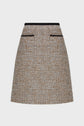 A tan tweed A-line mini skirt, or jupe courte, with black trim at the waist and two horizontal black-trimmed pockets on the front, displayed against a plain white background.
