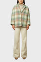A person wearing a pastel plaid manteau court en laine mélangée over a beige turtleneck sweater, cream-colored flared pants, and brown shoes, standing against a plain light background.