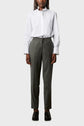 A person stands facing forward, wearing a white button-up shirt with ruffled collar and cuffs, gray tailored pants with a drawstring waist, and black loafers against a plain light background.