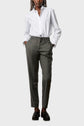 A person wearing a white button-up shirt tucked into gray dress pants with a drawstring waist, black loafers, and hands in their pockets stands against a plain light gray background.