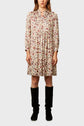 Woman wearing a knee-length, long-sleeve floral dress with a button-up front and collar, paired with black knee-high boots, standing against a plain light background.
