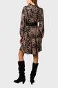 A woman wearing a black floral long-sleeve robe fluide with a black belt and black knee-high suede boots, standing and facing away from the camera.