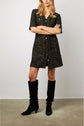 Woman wearing a black tweed dress with short sleeves and buttons down the front, paired with black knee-high boots, standing against a plain background.