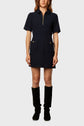 A person wearing a short-sleeve, navy blue textured dress with front pockets, a zip-up collar, and black knee-high boots, standing against a plain light background.