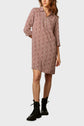 Woman wearing a knee-length, long-sleeved dress with a red and white floral pattern, paired with black lace-up combat boots, standing against a plain background.